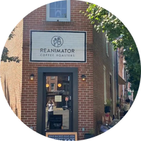 Brick building with 'Reanimator Coffee Roasters' sign and people outside